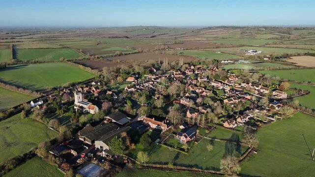 Drone footage of Hardwick village surrounded by green countryside fields on a sunny day