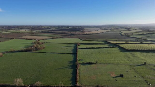 Aerial footage of rolling English country fields with a striking blue skyline and flat horizon