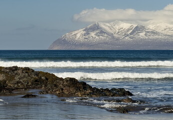 Russia. The Far East. The Kuril Islands. View of the basalt rock outcrops of volcanic origin on the sea sandy shore of Iturup island.