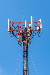 A close-up of a telecommunications tower with multiple antennas, set against a vibrant blue sky....