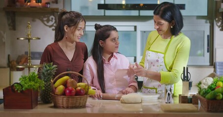 Indian happy young woman lady with cute teen cute girl hold roller rolling raw flour dough learn cook food indoor home adult mom teach kid child trying to bake cookies enjoy day modern home kitchen