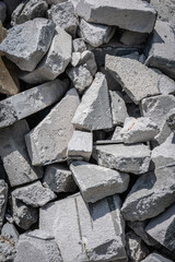 A close-up of a pile of broken concrete rubble. The image shows a variety of shapes and sizes of concrete fragments, with a focus on the rough textures and weathered surfaces.
