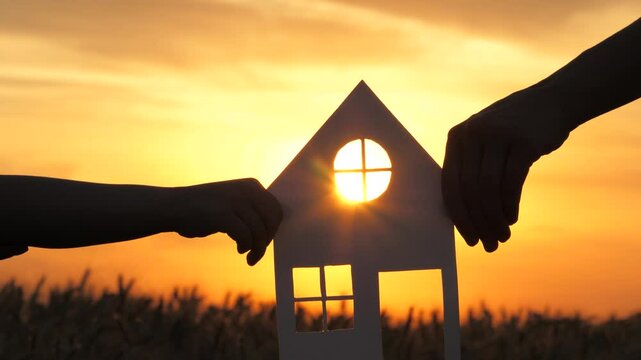 paper house ricky sunset. sunlight window. buying real estate living. House rent. happy family. paper house baby hands mom sunlight. holding hands together. mortgage. real estate concept. credit.
