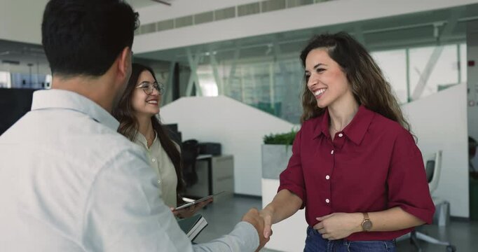 Three young European teammates finish collaborative meeting shaking hands expressing mutual respect and recognition for professional consultation, teamwork or brainstorm session with positive outcome