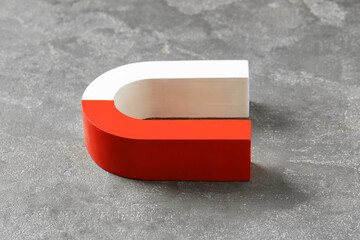 One horseshoe magnet on grey textured table, closeup