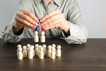 Woman with magnet attracting human figures at wooden table, closeup