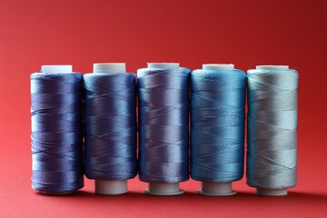 Spools of colorful sewing threads on red background