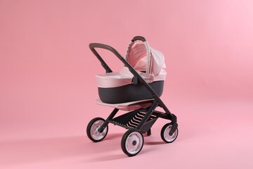 Stylish doll stroller on pink background. Kid's toy