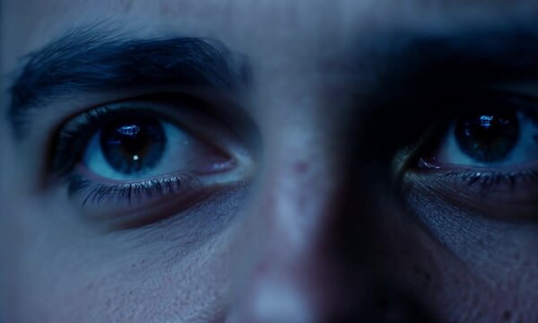A close-up shot of a man's eyes. His eyes are wide open and appear to be looking at something with a mixture of fear and anxiety.