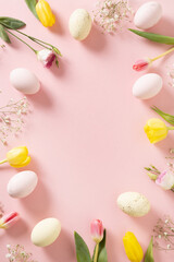 Easter frame with pastel pink eggs, chocolate candy sweets, yellow flowers and gypsophila on pink background. View from above. Flat lay. Happy Easter greeting card. Copy space.