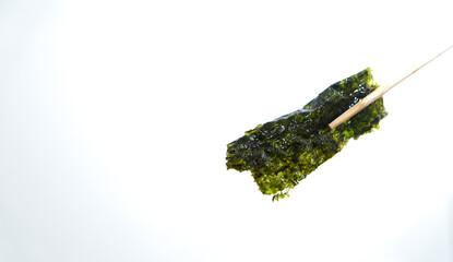 Crispy nori seaweed on white background with clipping path. Chopsticks hold a piece of crispy dried seaweed isolated on white background. Dry seaweed sheets.