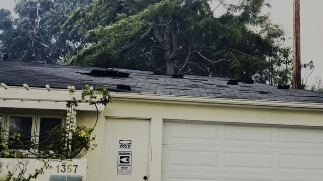 Heavy wind removing tiles from a house roof in Los Angeles, California, USA