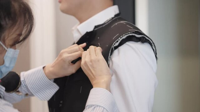 Close up young adult happy man asia people prepare custom tailoring made clothes for wedding party get dressed up tape scale measure try on full male suit at fitting room modern luxury shirt store.