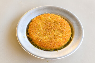 Pistachio kadayif on a plate. Turkish Dessert Kadayif with pistachio powder. Kunefe. Local name burma kadayif