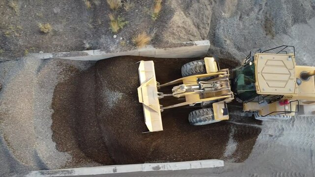 Front end loader manipulating cement from drone, aerial shot