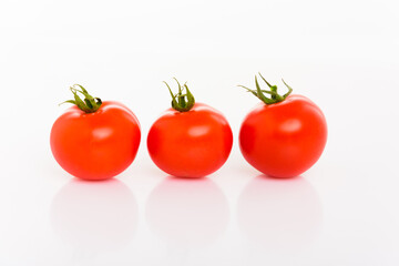 drei frische rote Tomaten mit Stengeln vor weißem Hintergund isoliert in Reihe