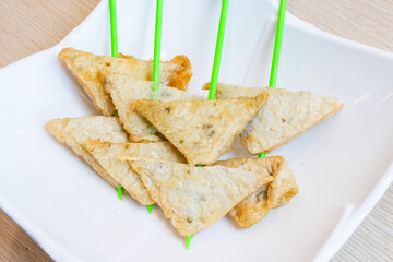 Fried tofu skin with seafood flavor are skewered on a green stick. Ready-made ingredients for shabu.