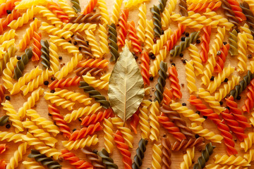Tri-Color Rotini Pasta with Black Pepper and Bay Leaf &ndash; Vibrant Spiral Pasta on Wooden Surface for publication, poster, calendar, post, screensaver, wallpaper, cover, website. High quality photography