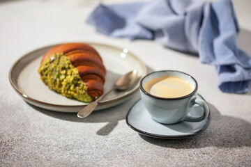 Croissant with pistachio butter and nuts and coffee on the table. Breakfast concept