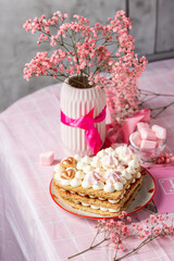 bento cake in the shape of a heart for two lovers, honey cake with buttercream and marshmallows, cake on a plate with hearts, pink gypsophila in a vase with a ribbon, light background, cake on a pink 