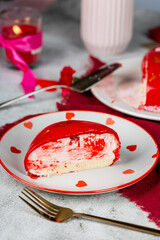 heart-shaped mousse cake in red glaze with gold decor on a white plate, red and pink carnations, roses, gypsophila in a vase, Valentine's Day cake, birthday, light background, food photo