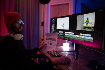Editing a video project with dual monitors in a modern workspace during evening hours