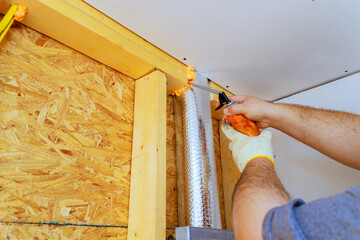 Worker is applying foam insulation to vent pipe in residential area, on energy efficiency during...