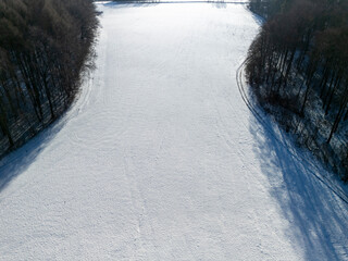 Aerial view of a snow-covered landscape, peaceful and serene, with trees lining the edge, perfect...