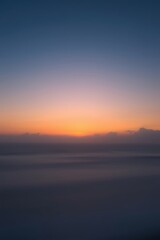 Obraz premium Serene sunset over calm ocean, blurred horizon.