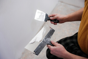 The worker processes the wall with putty. Hand with putty knife repair wall, Hand with a spatula,...