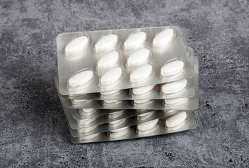 Medical pills in blister pack on grey background.