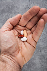 Pills in hand on a grey background. Close-up.