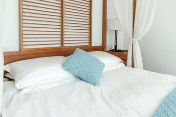 Simple and elegant bedroom with a canopy bed, draped with light white curtains that add a sense of...