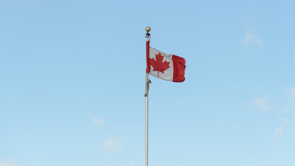 Maple Leaf, flag of Canada wrapped partly on a pole on a blue sky