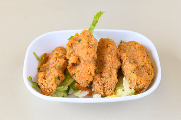 Cig kofte (raw meatball) with lettuce, tomato, pickle and lemon, hot Chee kofta. Turkish local raw food concept.Table scene of assorted take out or delivery foods. Doritoslu duble cig kofte durum.