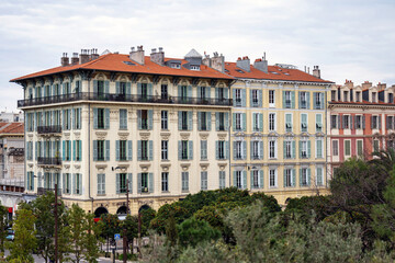 Fototapeta premium Red and orange buildings in Nice, France, park with green park trees