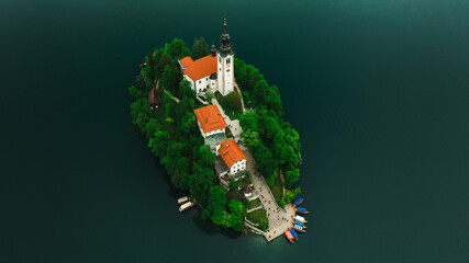 Aerial view of Church of the Assumption of Mary in the center of the lake Bled. Flying around small...