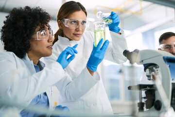 Two female scientists analyzing chemical substance in laboratory.