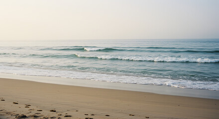 Obraz premium Sandy beach with waves lapping onto the shore.
