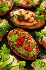 Sweet potato toasts with various vegetarian toppings, focus on the  toast with  avocado paste and baked tofu in the middle, close-up view.