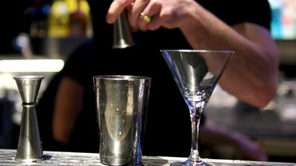 Bartender, hands close-up, preparing alcoholic cocktail, pouring into measured metal shot glass and pouring into shaker. Vertical format. High quality 4k footage