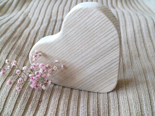 wooden heart lying on its side and gypsophila flowers on beige background
