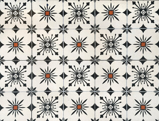 Colonial heritage patterned tiles in random geometric floral, star, and ornamental patterns. Handmade colonial tiles, or old heritage tiles in black, white, and orange paint.