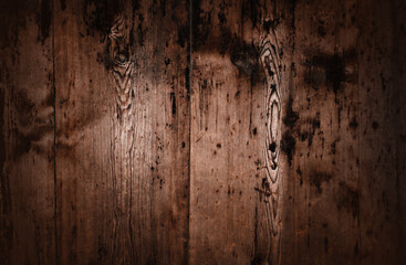 A close up of very old wooden planks with a dark, aged, and weathered texture. The rough surface features deep cracks, visible knots, and a natural distressed look, adding a vintage and rustic charm.