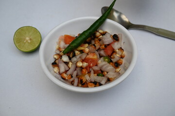 Grilled corn Chaat. Indian style corn salad that's sweet, spicy and tangy. It is mixed with chaat masala, roasted cumin powder, red chili powder, coriander leaves, onion and tomatoes. Indian snacks.