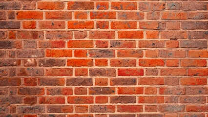A weathered red brick wall with visible cracks and aged details.