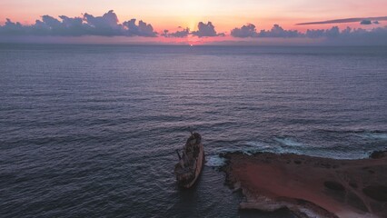Serene sunset over ocean with shipwreck in Paphos, Cyprus