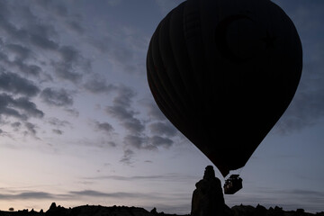 Hot air balloon is on the air at Cappadocia. Silhouette photo at sunrise.