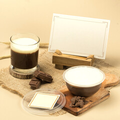 A beautifully presented chocolate pudding dessert with a creamy topping sits next to a glass filled with a dark drink on a rustic table setting