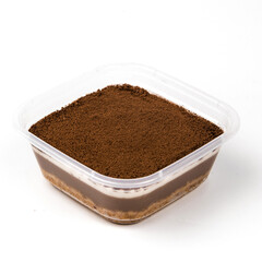 Layers of rich chocolate pudding cake dessert topped with fine cocoa powder are beautifully presented in a clear container on a plain surface